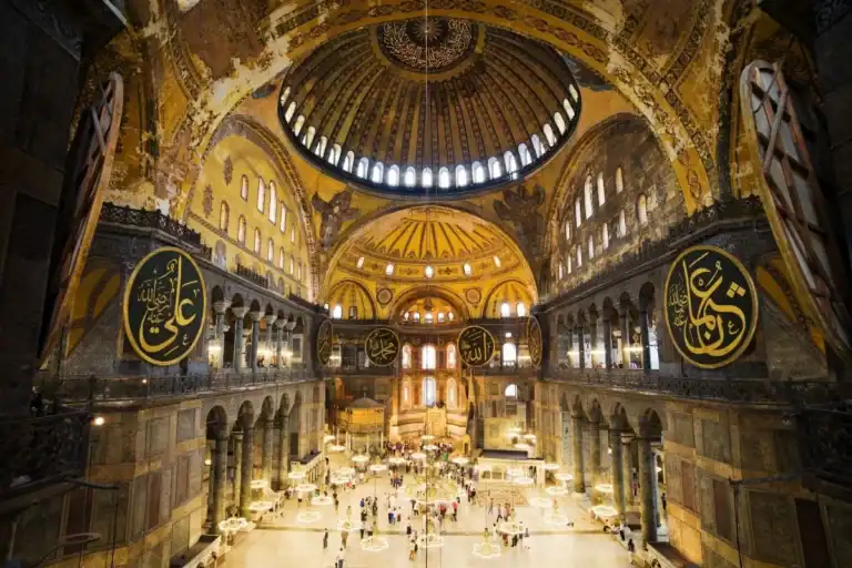 The Complete First-Timer’s Guide to Visiting Istanbul 1 Hagia Sophia interior in Istanbul, Turkey, showing golden dome, Arabic calligraphy, chandeliers, and visitors