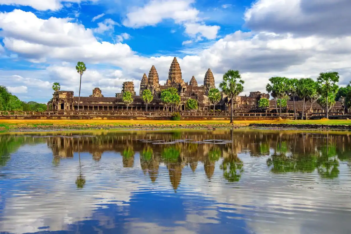 Angkor Wat temple in Siem Reap, Cambodia, reflected in a peaceful pond under a blue sky.