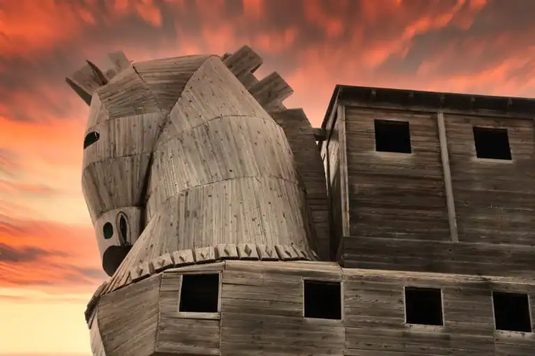 Wooden Trojan Horse replica at ancient Troy beneath a vivid orange sunset, highlighting the legendary historic landmark.